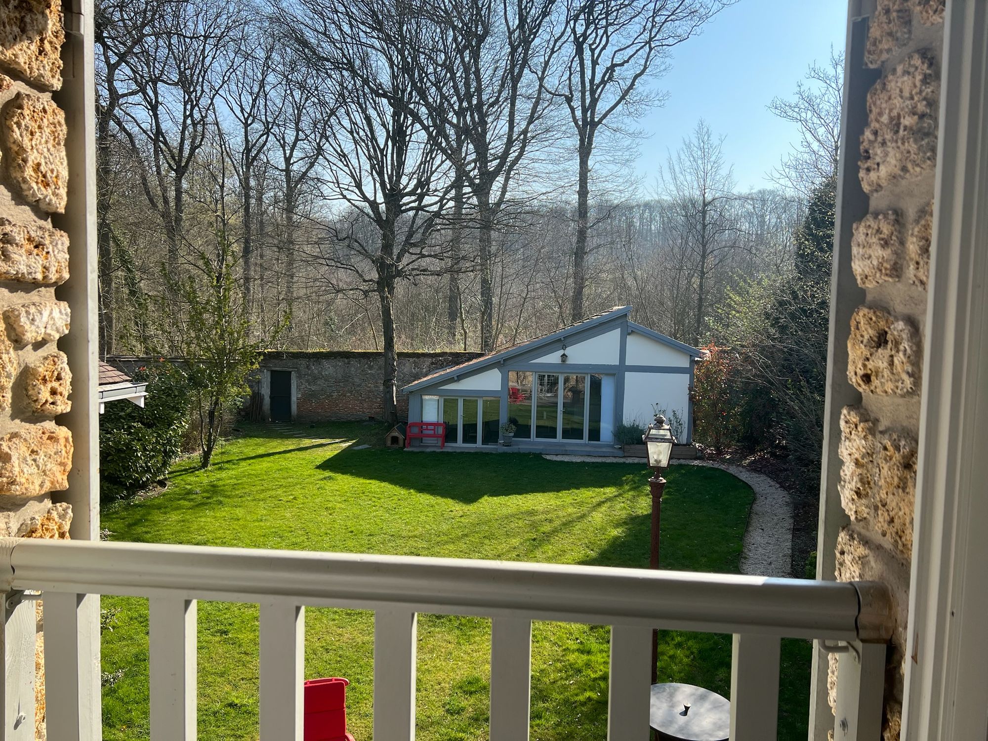 From an upstairs window: the lawn, the guest cottage, the old stone wall with its door, and the forest beyond