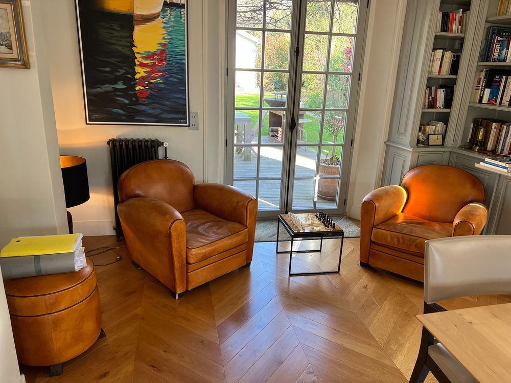 Leather club chairs by French doors open onto the terrace